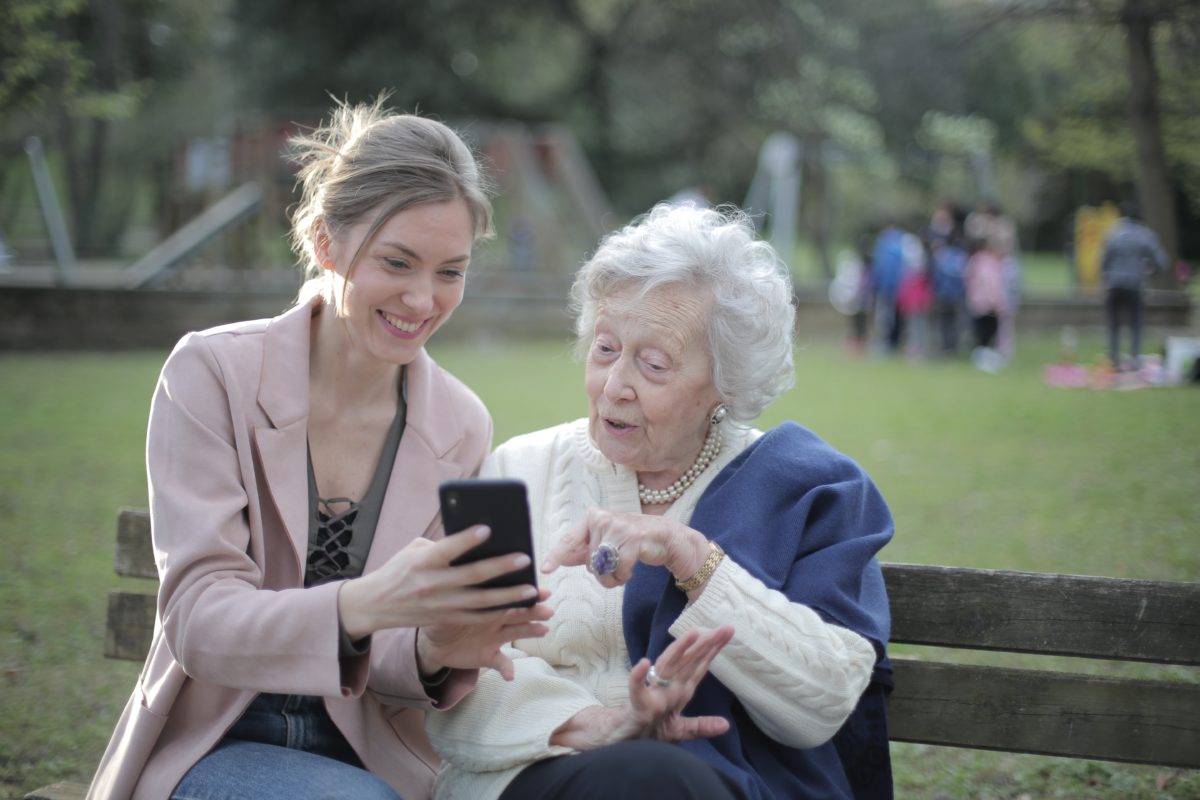 Older and middle aged women sitting on a bench looking at a phone